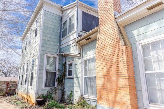 doorway to property featuring visible vents, a chimney, and fence