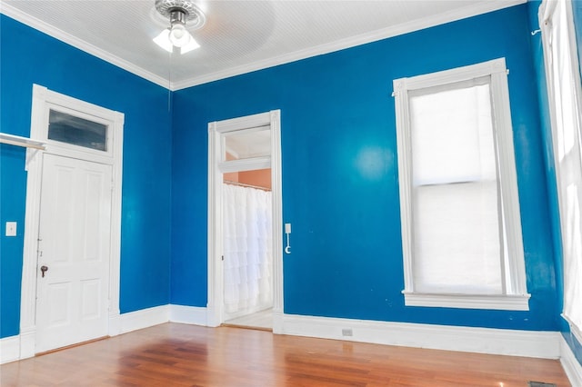 empty room featuring baseboards, crown molding, ceiling fan, and wood finished floors