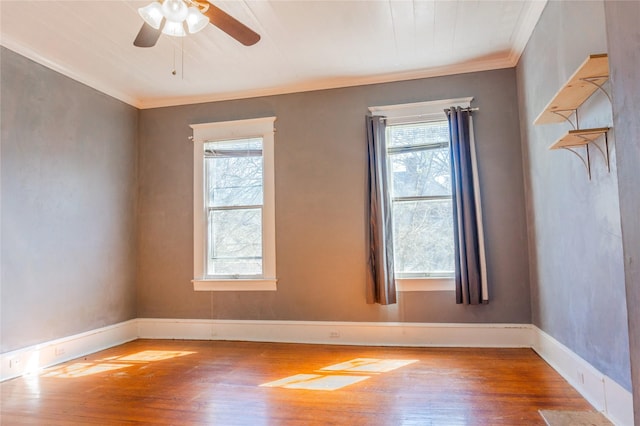 spare room with a healthy amount of sunlight, crown molding, and hardwood / wood-style flooring