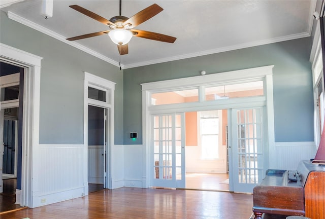 entryway featuring wood finished floors, a wainscoted wall, french doors, and ornamental molding