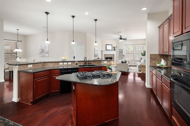 kitchen with open floor plan, a center island, black appliances, a fireplace, and a sink