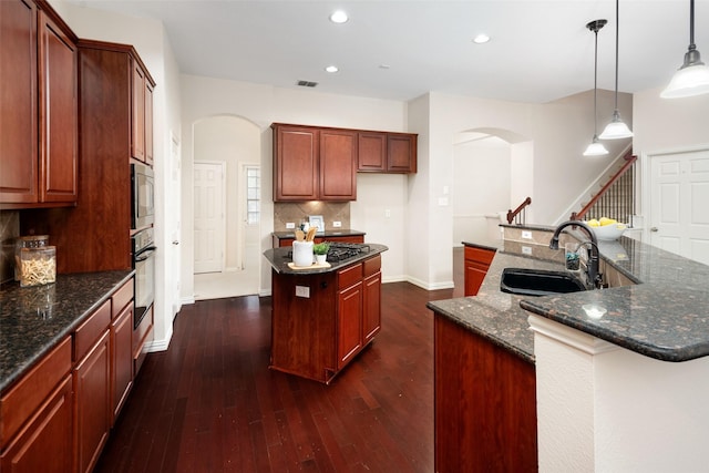 kitchen featuring visible vents, arched walkways, a spacious island, oven, and a sink