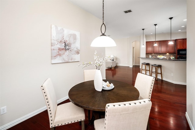 dining area featuring arched walkways, recessed lighting, visible vents, baseboards, and dark wood-style floors