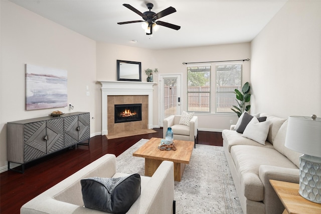 living room featuring baseboards, a fireplace, a ceiling fan, and wood finished floors