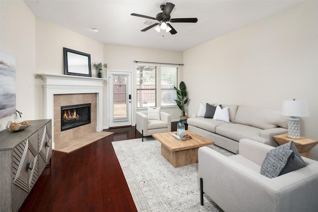 living room featuring a ceiling fan, a tile fireplace, and wood finished floors