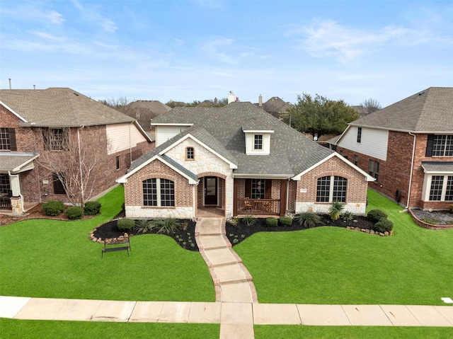 view of front facade featuring covered porch, brick siding, stone siding, roof with shingles, and a front yard