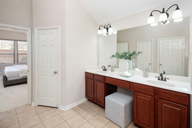 ensuite bathroom with tile patterned flooring, vaulted ceiling, and a sink