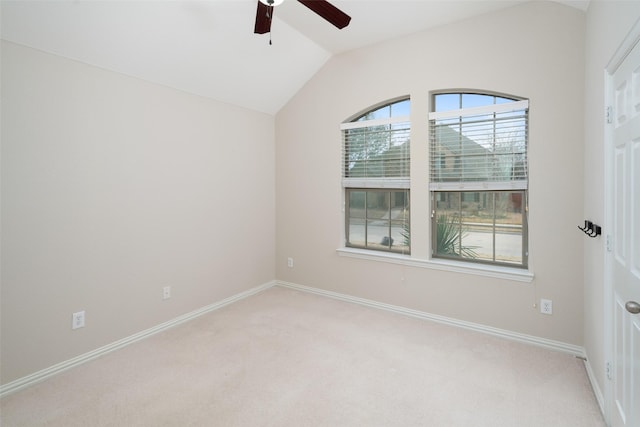 empty room featuring light carpet, vaulted ceiling, baseboards, and ceiling fan