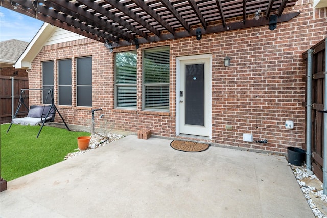 doorway to property with brick siding, a patio area, fence, and a pergola