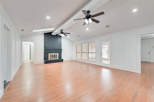 unfurnished living room with light wood finished floors, visible vents, a decorative wall, lofted ceiling with beams, and a brick fireplace