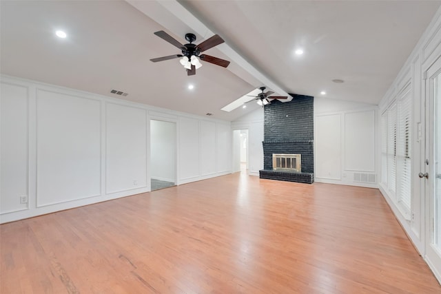 unfurnished living room with vaulted ceiling with beams, a fireplace, a decorative wall, and visible vents