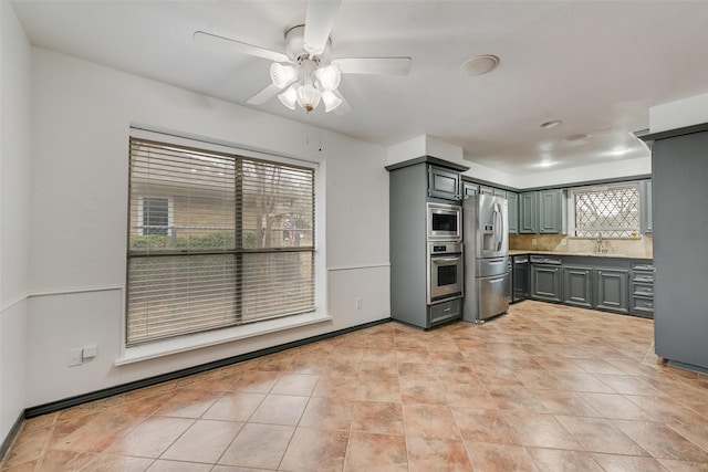 kitchen with appliances with stainless steel finishes, decorative backsplash, a sink, and gray cabinetry