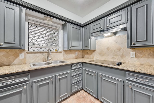 kitchen featuring decorative backsplash, gray cabinets, black electric cooktop, under cabinet range hood, and a sink