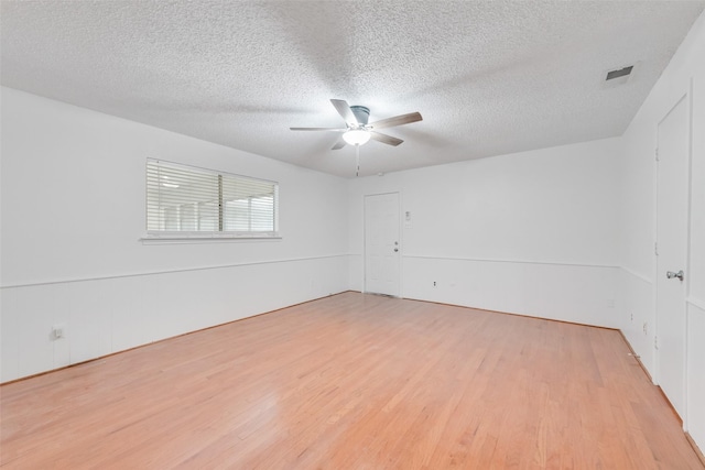 empty room featuring ceiling fan, a textured ceiling, light wood-type flooring, and visible vents