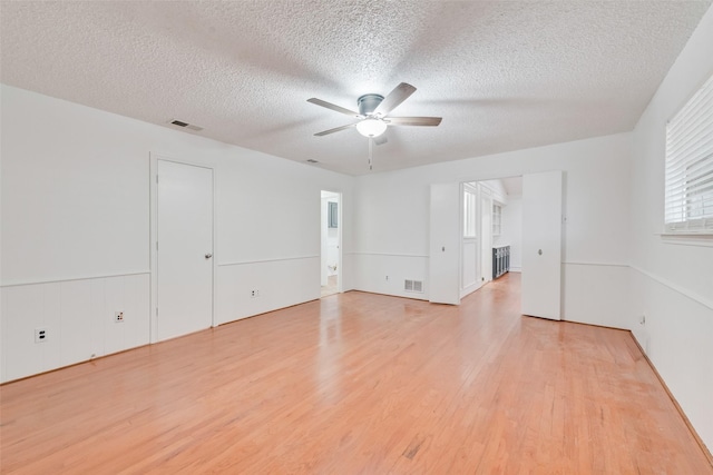 spare room with a ceiling fan, visible vents, a textured ceiling, and light wood finished floors