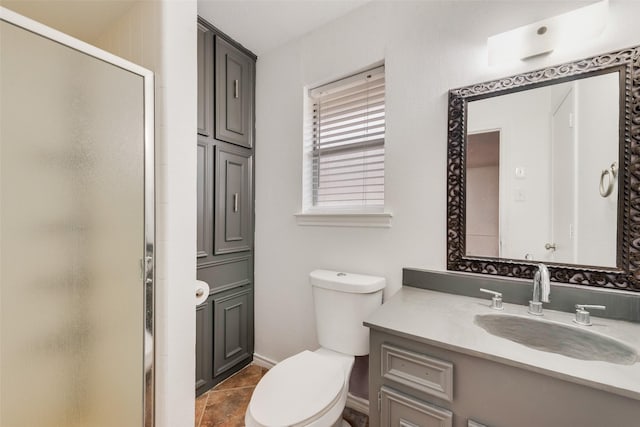 bathroom with vanity, a shower stall, toilet, and baseboards