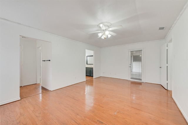 spare room featuring crown molding, visible vents, a ceiling fan, light wood-type flooring, and baseboards