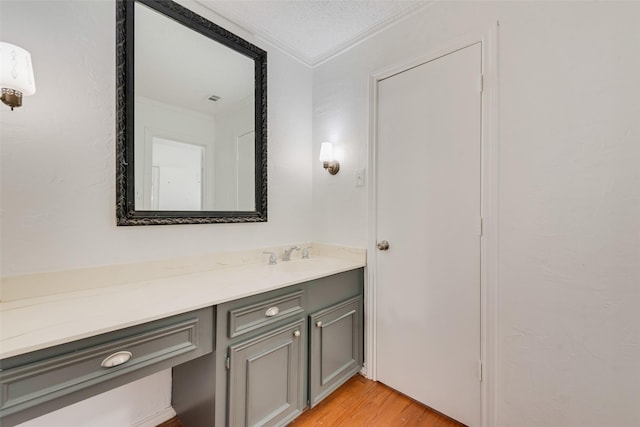 bathroom with visible vents, ornamental molding, wood finished floors, a textured ceiling, and vanity