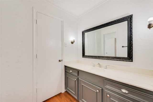 bathroom featuring a textured ceiling, ornamental molding, wood finished floors, and vanity