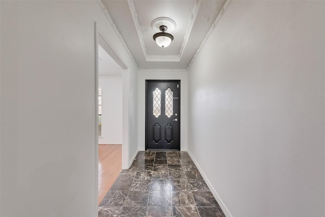 doorway with marble finish floor, baseboards, a raised ceiling, and ornamental molding