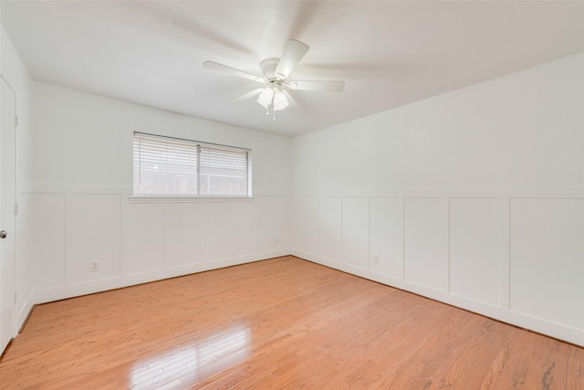 unfurnished room featuring light wood-type flooring, wainscoting, and ceiling fan