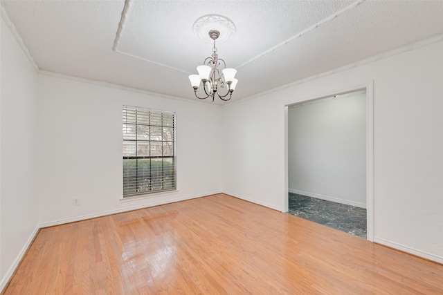 unfurnished room featuring a notable chandelier, baseboards, and wood finished floors