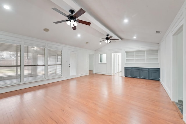 unfurnished living room with light wood finished floors, visible vents, vaulted ceiling with beams, built in shelves, and a decorative wall