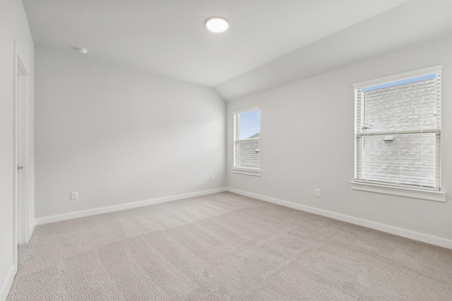 unfurnished room featuring lofted ceiling, light colored carpet, and baseboards