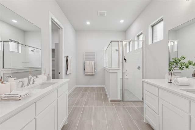 bathroom with baseboards, tile patterned floors, a sink, a shower stall, and two vanities