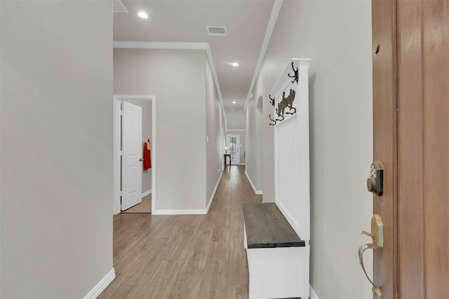 corridor featuring ornamental molding, baseboards, visible vents, and light wood finished floors