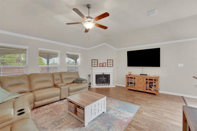 living room with ornamental molding, visible vents, light wood-style floors, and a fireplace with raised hearth