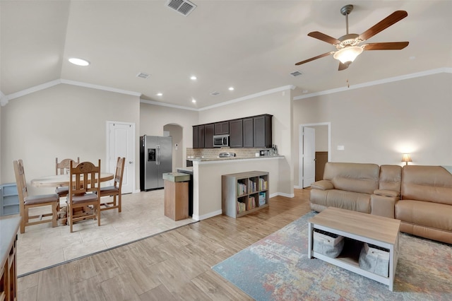 living area with arched walkways, light wood-type flooring, lofted ceiling, and visible vents