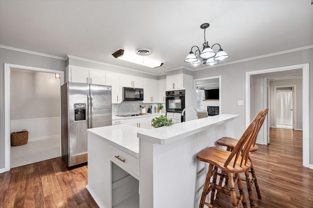 kitchen with visible vents, a breakfast bar, light countertops, crown molding, and black appliances