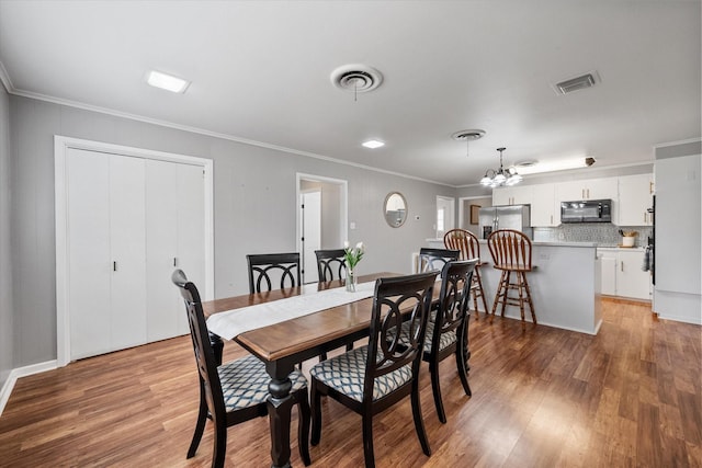 dining space featuring light wood-type flooring, visible vents, and crown molding