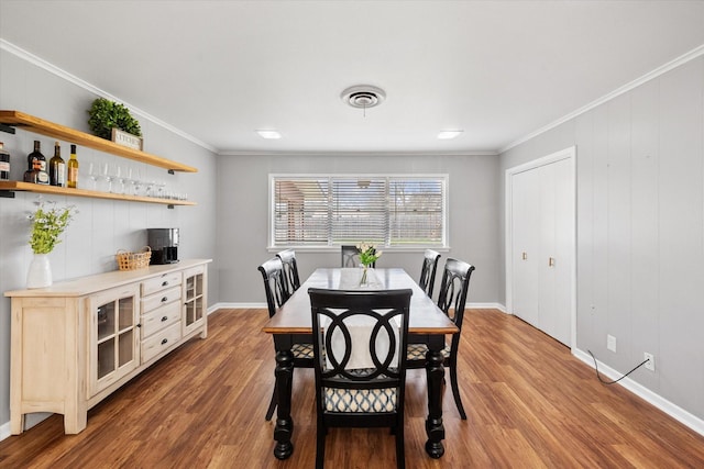 dining space with ornamental molding, visible vents, baseboards, and wood finished floors