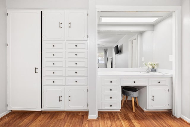 bathroom with baseboards, wood finished floors, and vanity