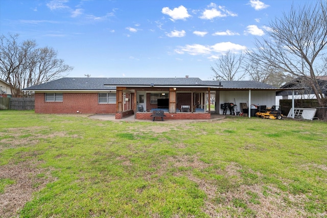 rear view of property with a patio, a yard, fence, and brick siding