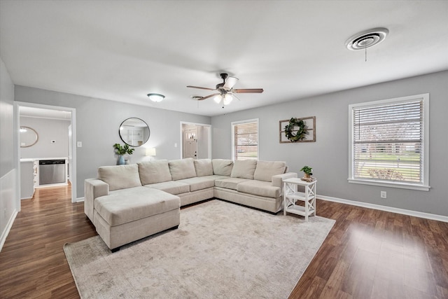 living area with a healthy amount of sunlight, dark wood-style floors, and baseboards