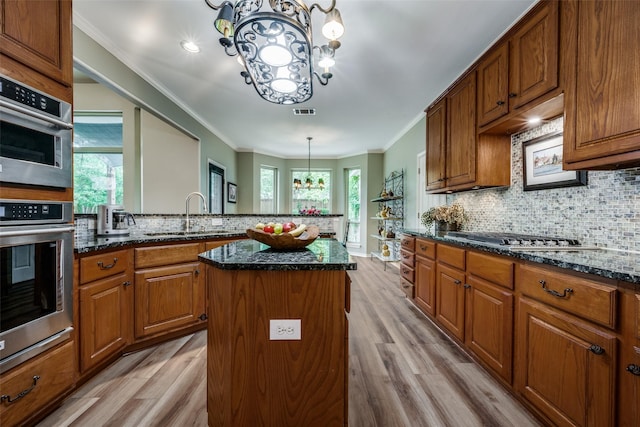 kitchen featuring a sink, a center island, appliances with stainless steel finishes, decorative backsplash, and an inviting chandelier