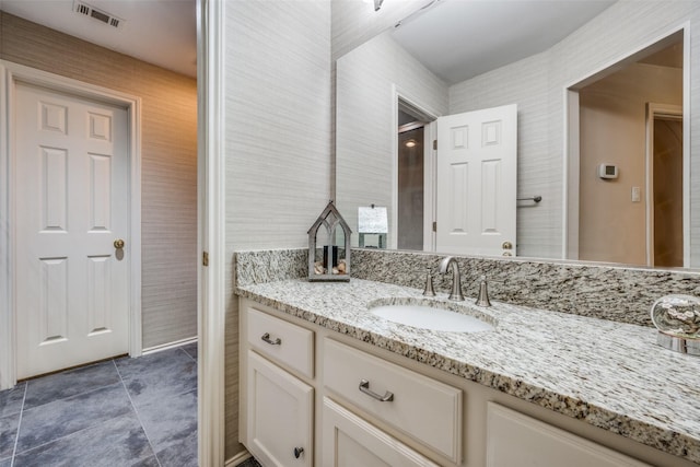 bathroom with wallpapered walls, tile patterned floors, visible vents, and vanity