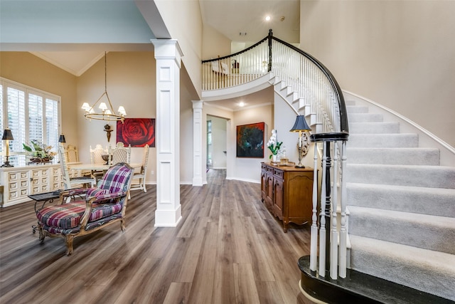 entryway with ornamental molding, stairway, wood finished floors, and decorative columns