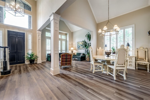 dining area with ornamental molding, wood finished floors, decorative columns, and a notable chandelier