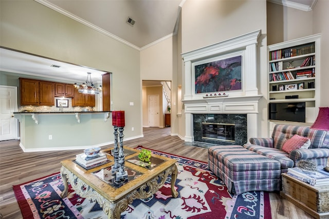 living area with a premium fireplace, visible vents, crown molding, and wood finished floors