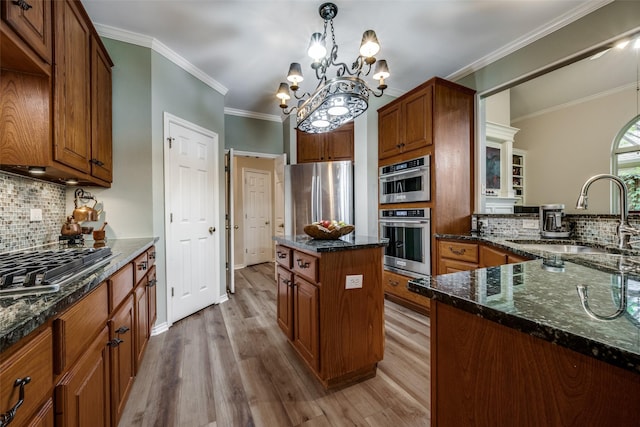 kitchen with appliances with stainless steel finishes, dark stone counters, crown molding, and a sink