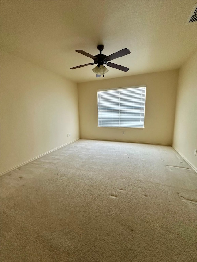 carpeted empty room with ceiling fan, a textured ceiling, visible vents, and baseboards