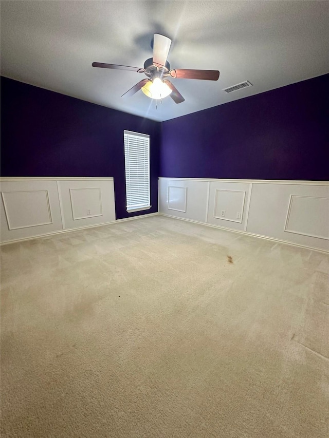 spare room with ceiling fan, a textured ceiling, visible vents, and carpet flooring