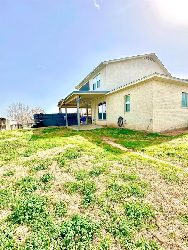 back of property featuring a patio area, a lawn, brick siding, and stucco siding