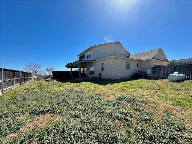 rear view of house with a fenced backyard and a yard