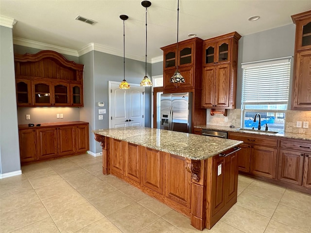 kitchen featuring stainless steel fridge, visible vents, a kitchen island, ornamental molding, and a sink