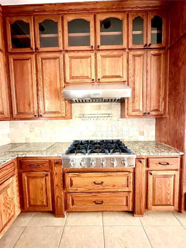 kitchen with backsplash, stainless steel gas stovetop, under cabinet range hood, and light stone countertops